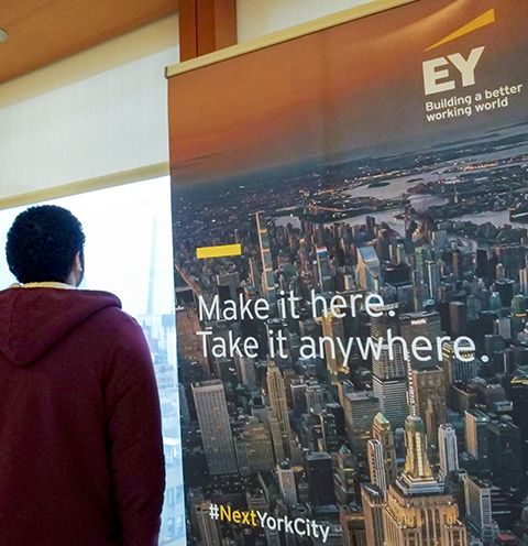 A student looks at a sign that says EY: Make it here. Take it anywhere.